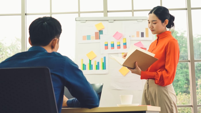 Asian businesswoman presenting project progress on whiteboard